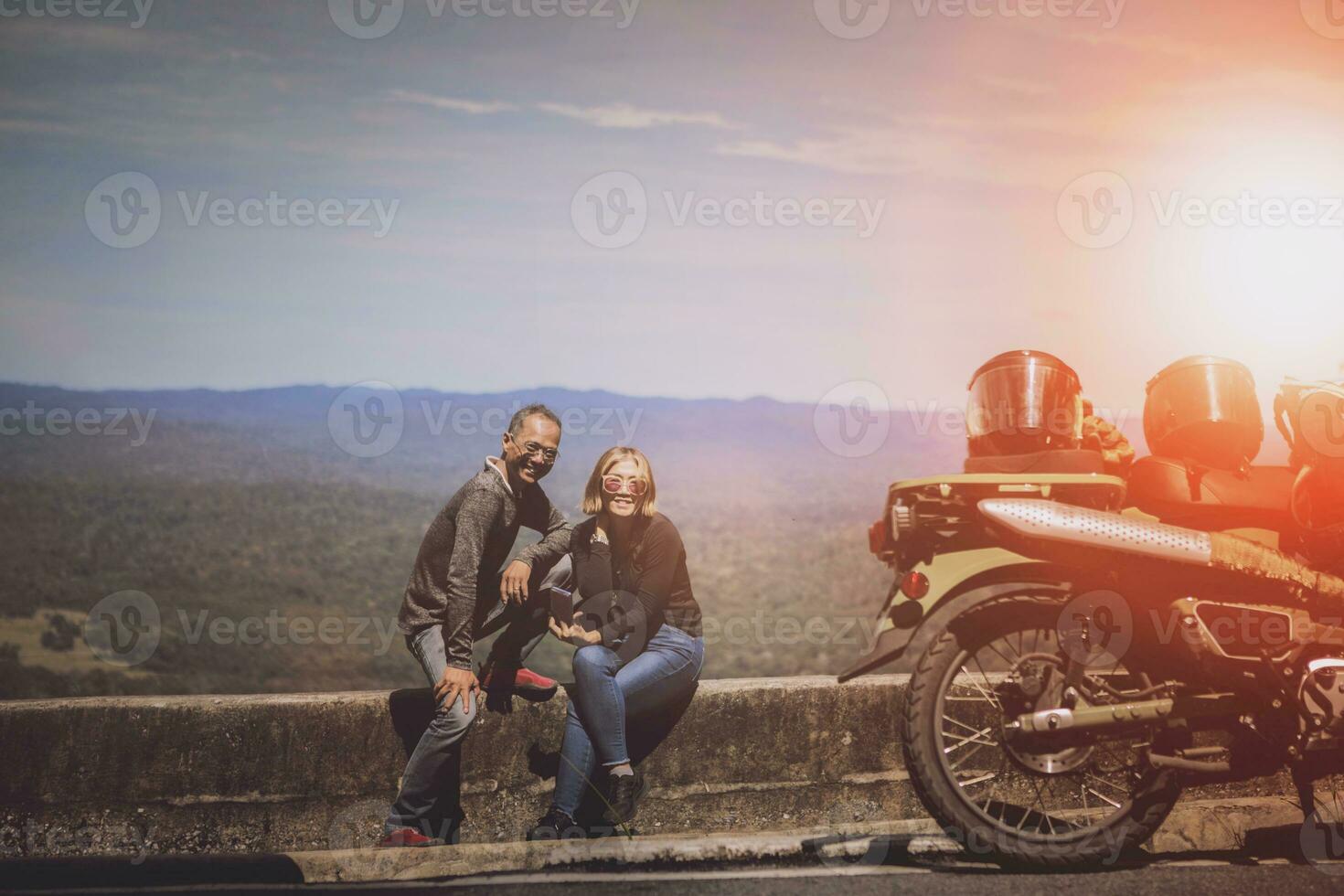 par av cyklist toothy leende med lycka bredvid små motorcykel på reser destination foto