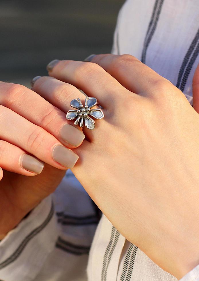 blomma form silverring på ett finger. intressant smyckedesign foto