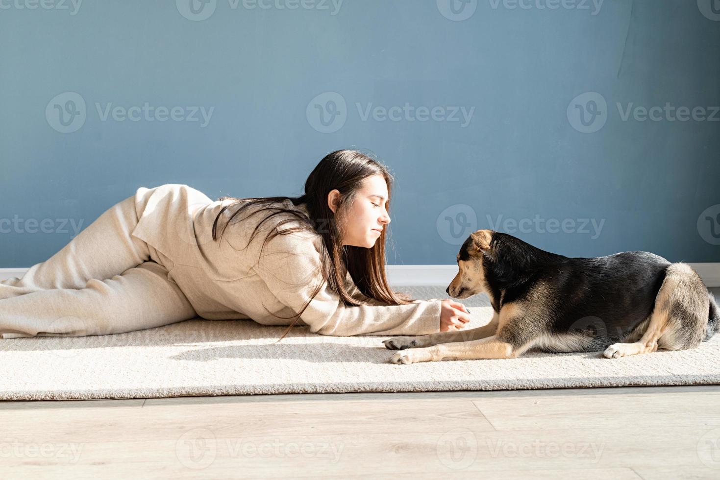 vacker kvinna med lekfull hund som omfamnar hemma foto