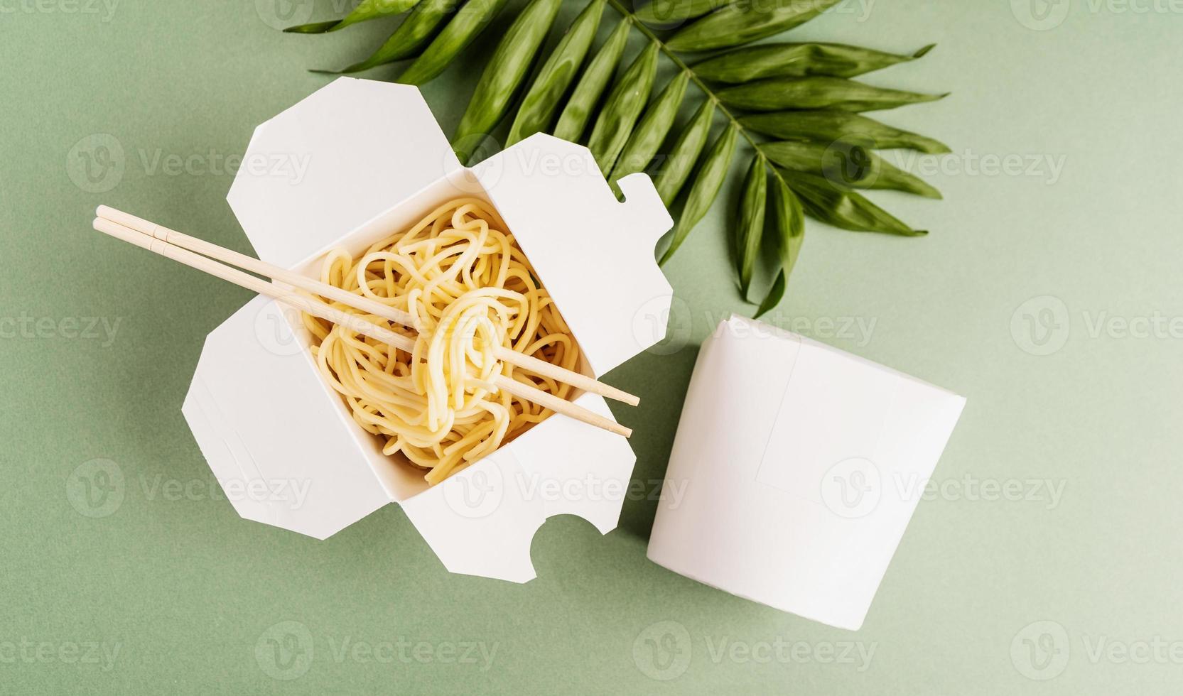 öppnad wokpapperslåda med nudlar och ätpinnar foto