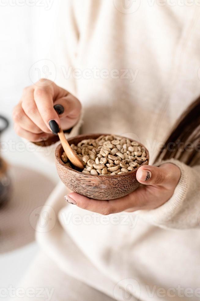 kvinnans handhållande skål med gröna kaffebönor foto