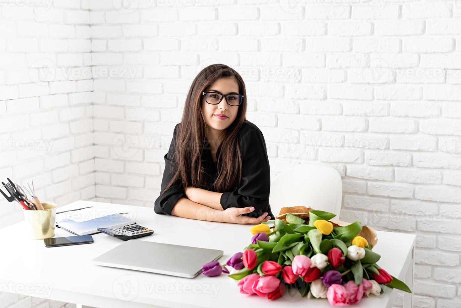 brunett affärskvinna som arbetar med blommor på kontoret foto