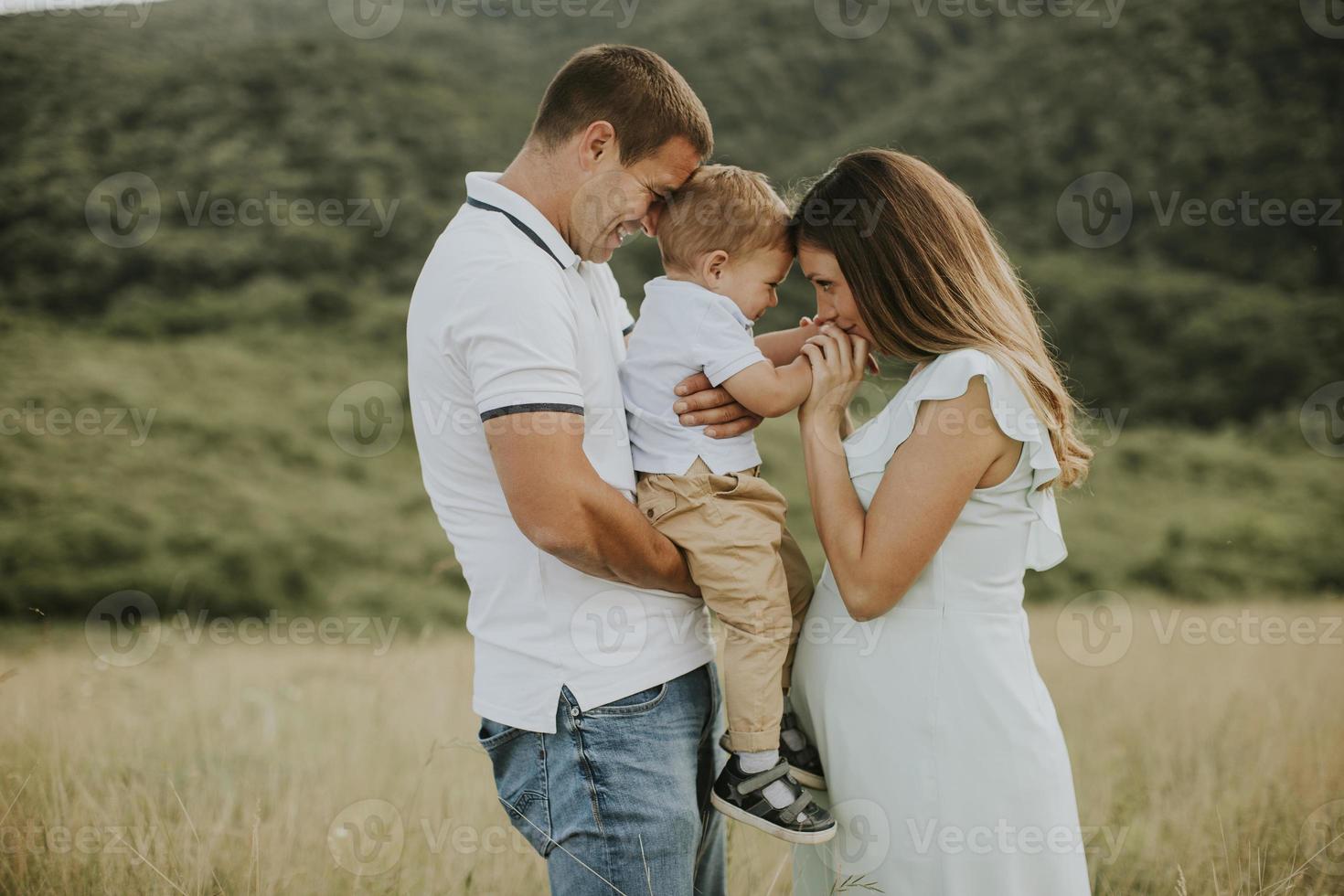 ung familj med söt liten pojke som har kul utomhus i fältet foto