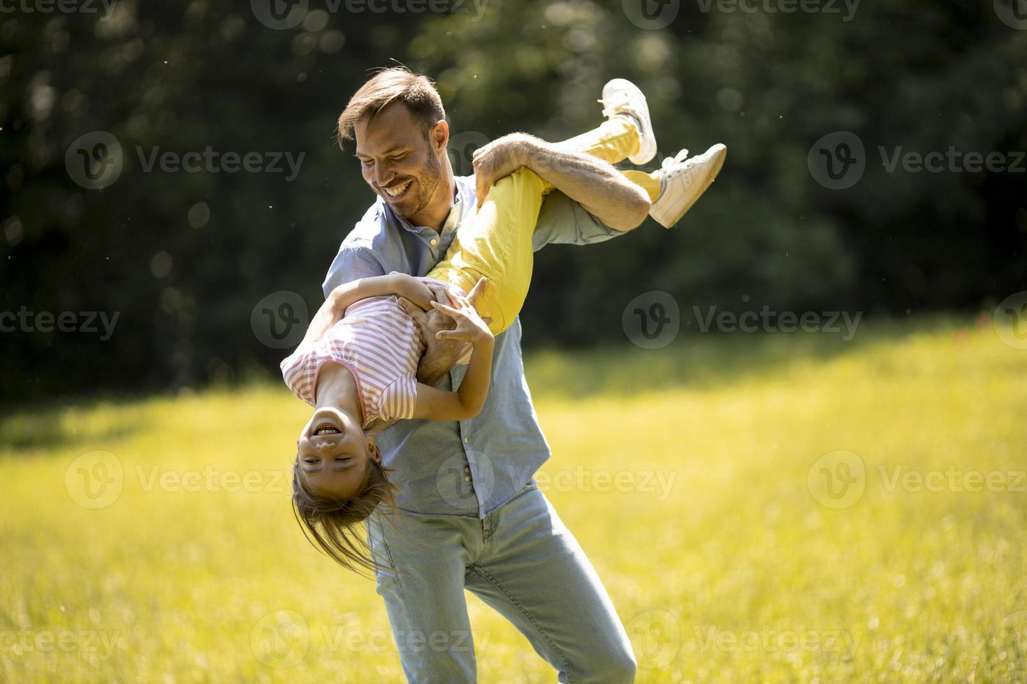 far med dotter som har kul på gräset i parken foto