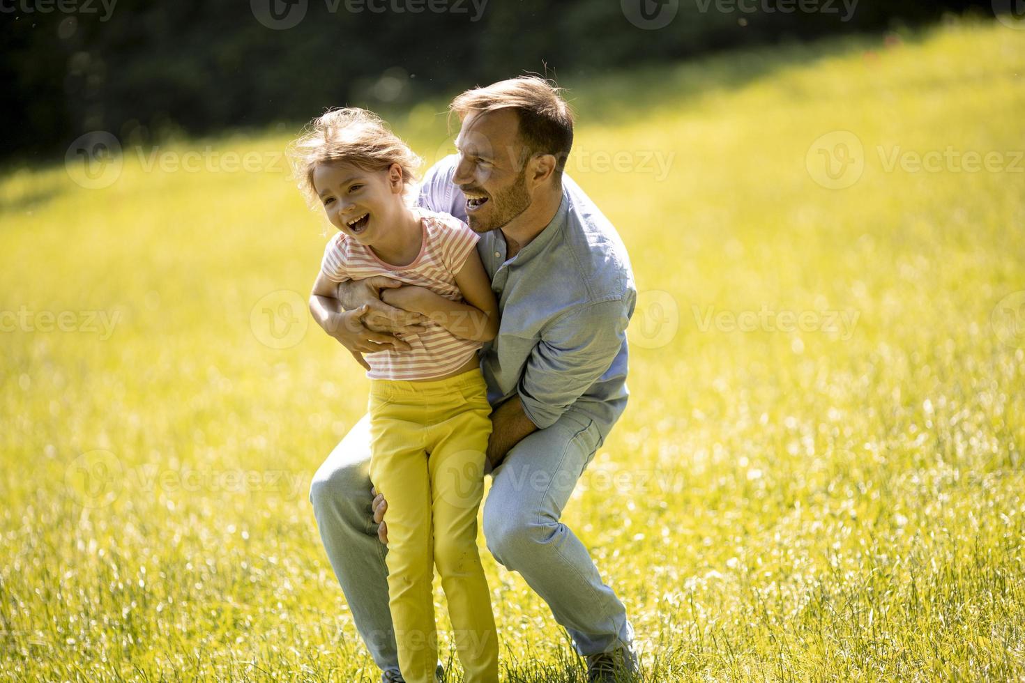 far med dotter som har kul på gräset i parken foto