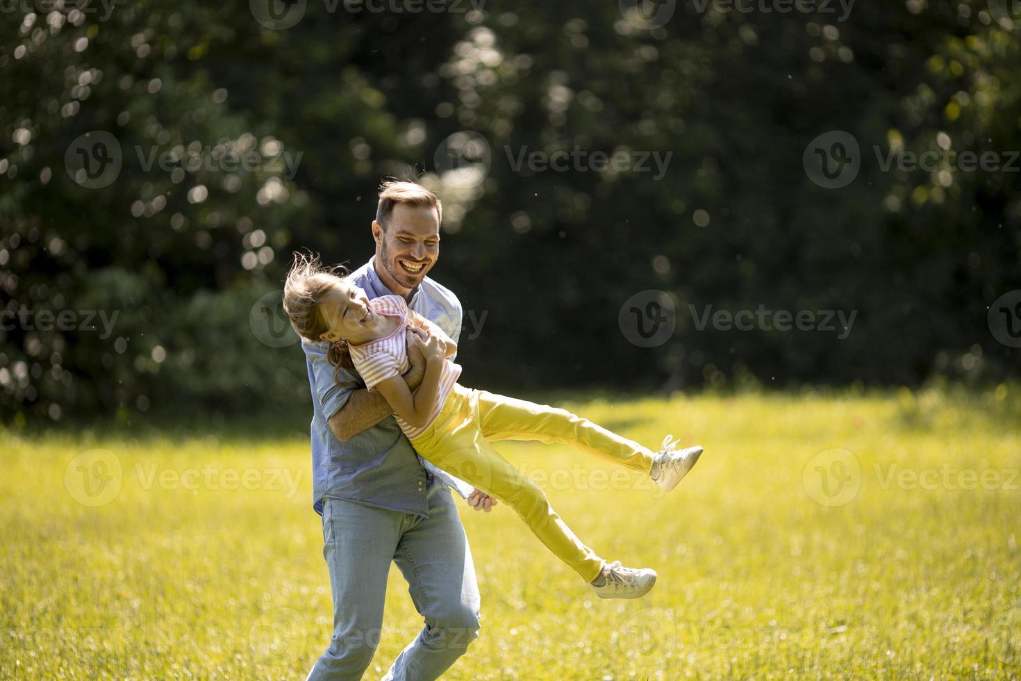 far med dotter som har kul på gräset i parken foto