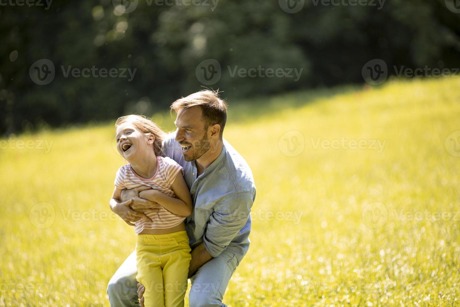 far med dotter som har kul på gräset i parken foto