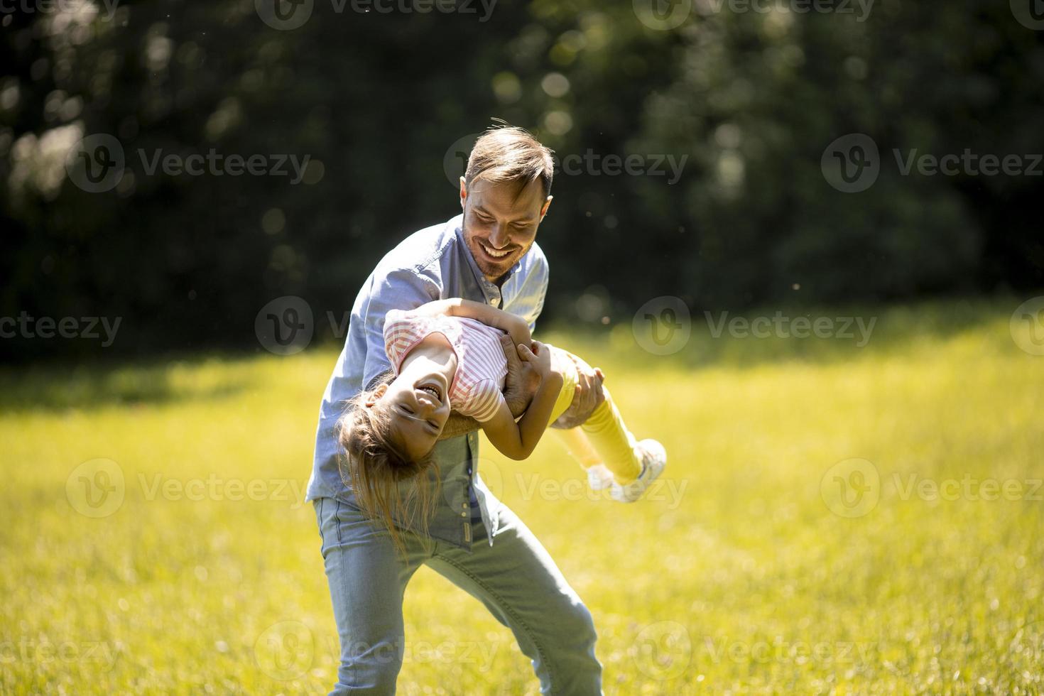 far med dotter som har kul på gräset i parken foto