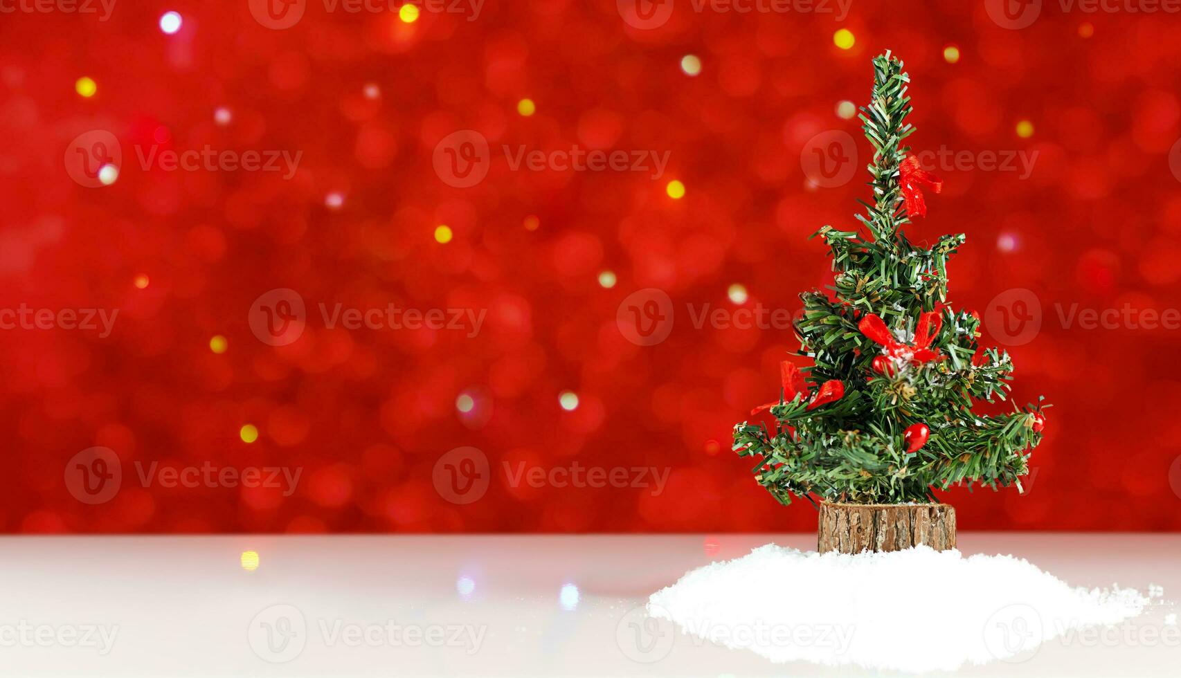 leksak jul träd med röd dekor på en vit tabell mot en bakgrund av röd och flerfärgad defocused lampor foto