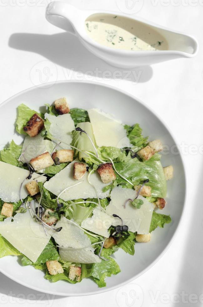 Caesarsallad med parmesanost och krutonger på träbord foto