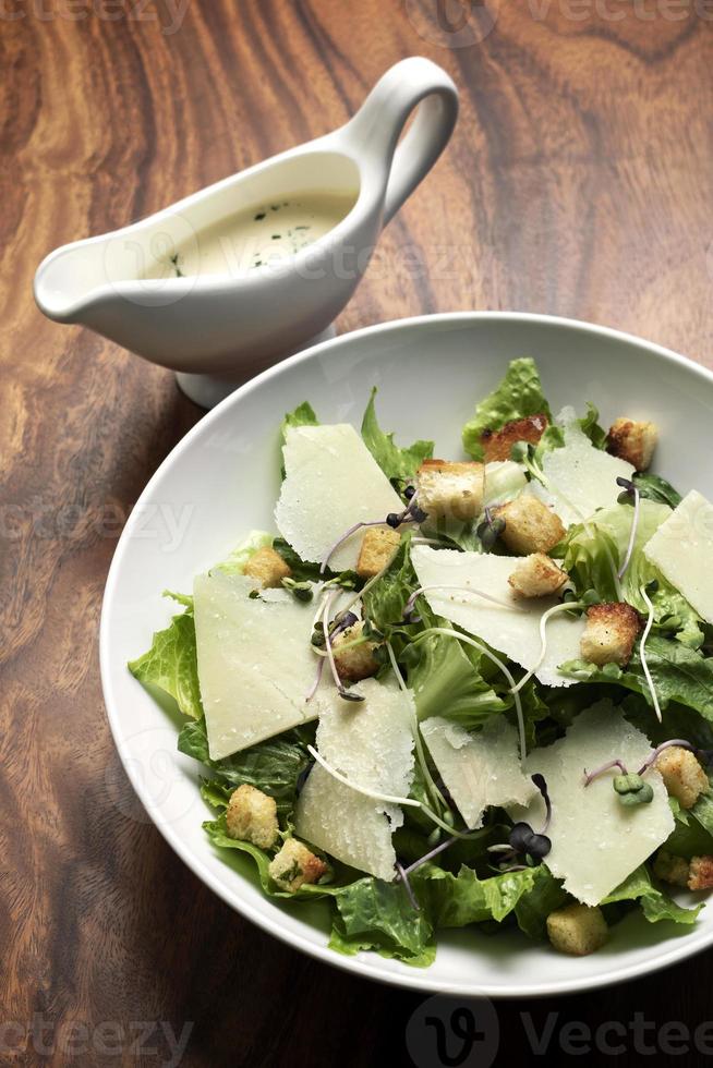 Caesarsallad med parmesanost och krutonger på träbord foto