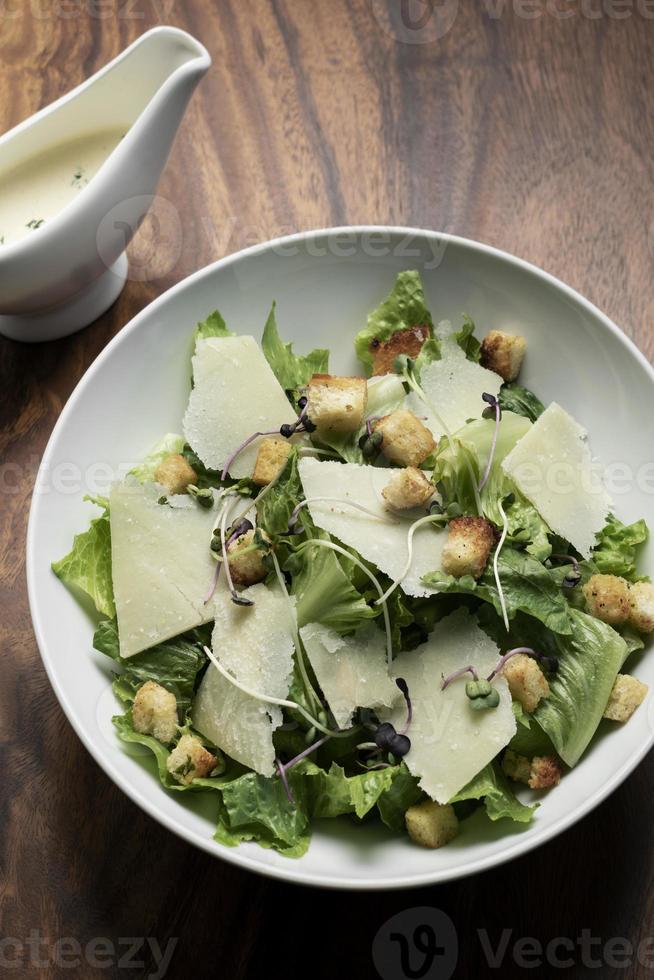 Caesarsallad med parmesanost och krutonger på träbord foto