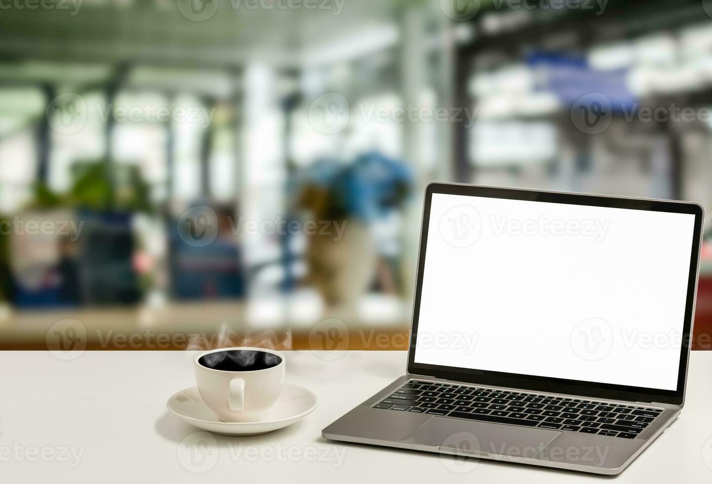 en tom vit skärm bärbar dator och kaffe kopp är placerad på en vit skrivbord i ett kontor. de begrepp för företag, teknologi, internet, design, och konst. närbild, selektiv fokus, suddig bakgrund foto