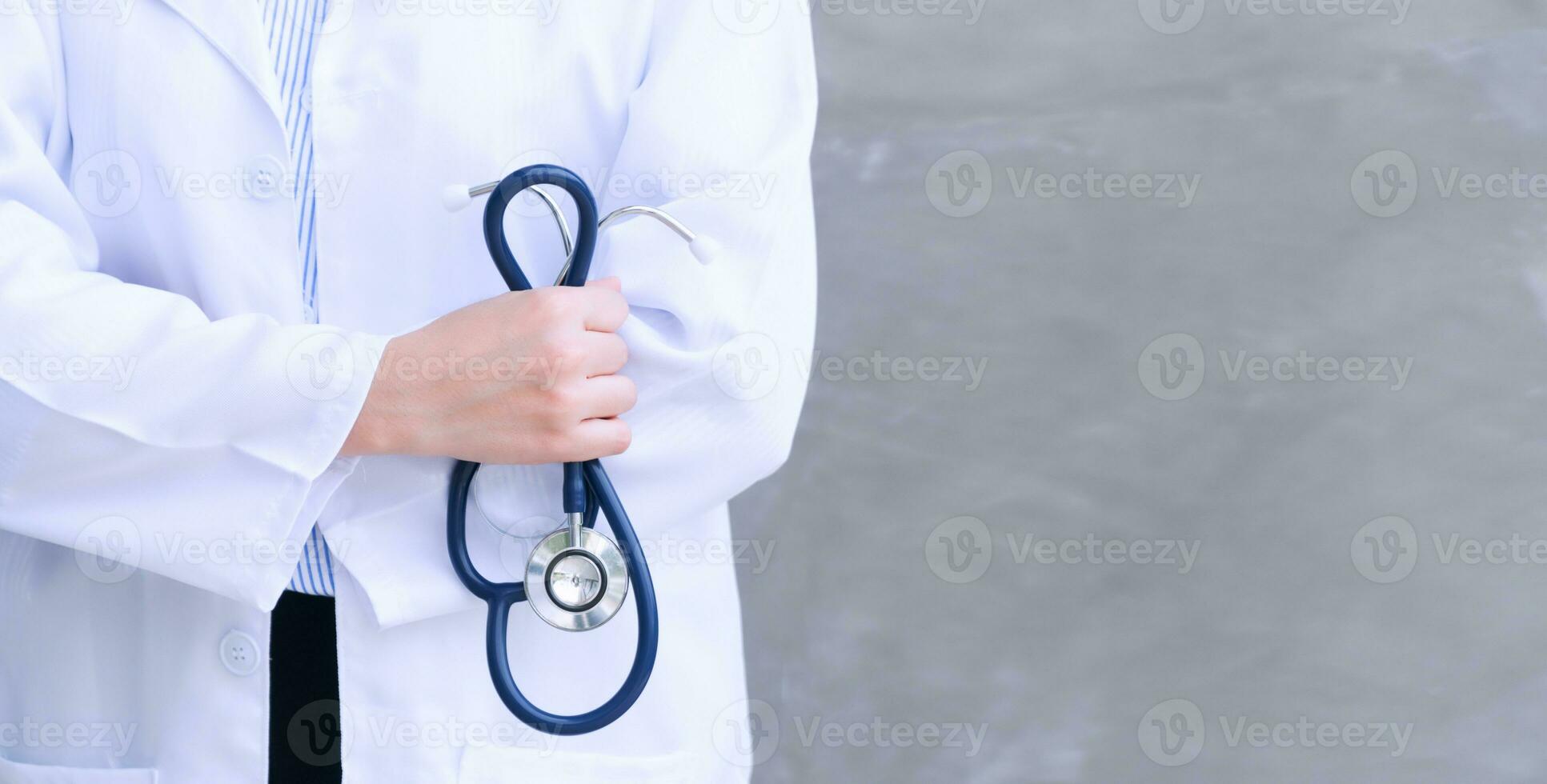 begrepp av sjukvård och medicin. ung kvinna läkares hand innehav stetoskop på grå bakgrund med kopia Plats. foto