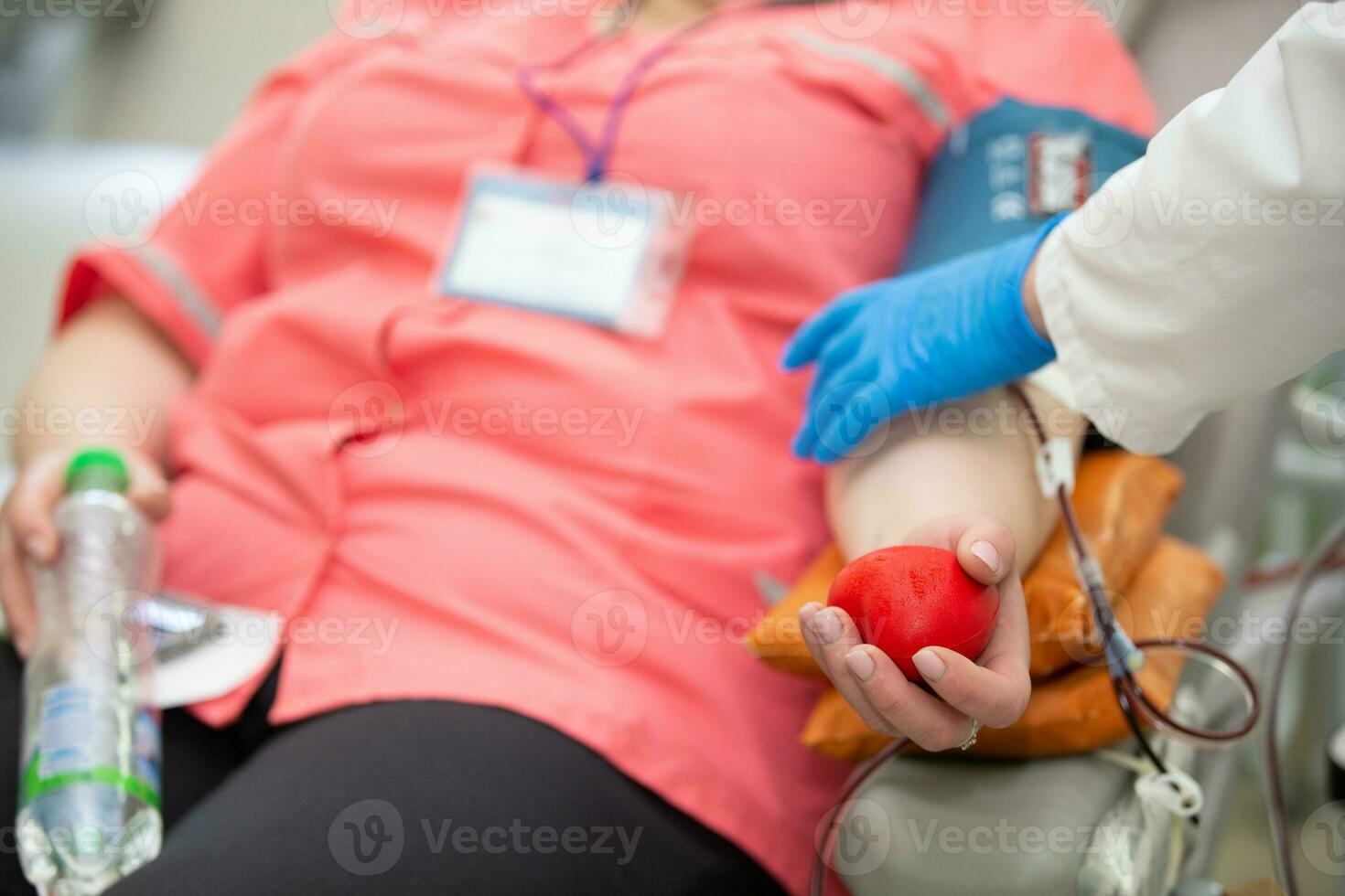 närbild av en kvinnas hand klämma en boll ut av påfrestning medan donera blod på en blod donation Centrum. foto