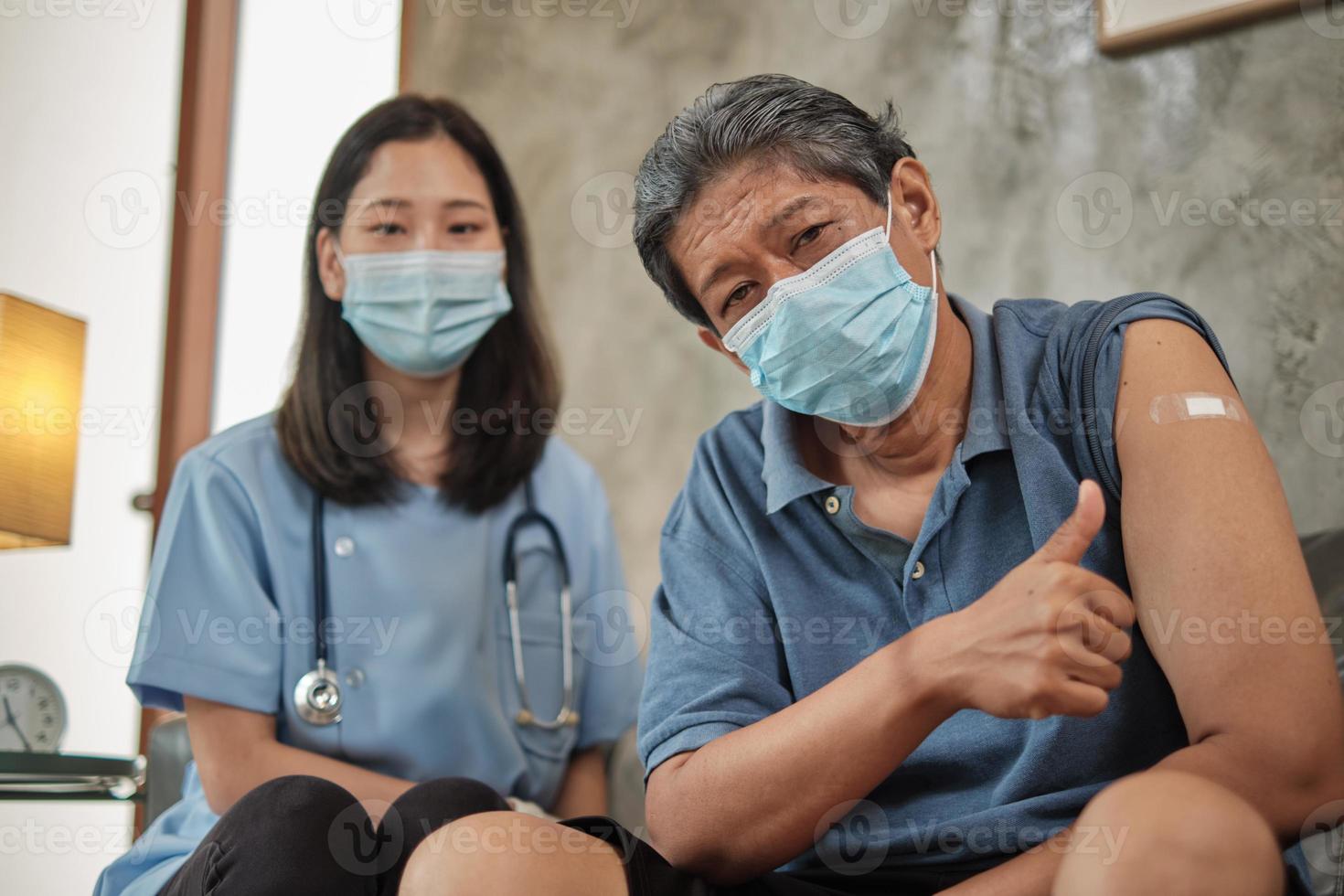 äldre patient med ansiktsmask tummen upp vid vaccination. foto