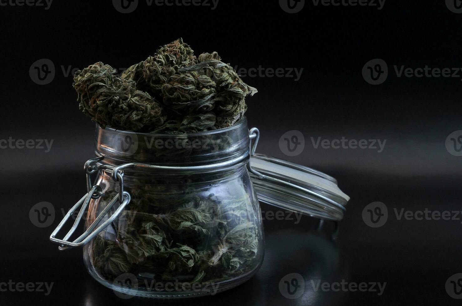 noir fortfarande liv med glas murare burk full av torr medicinsk cannabis knoppar på svart bakgrund foto