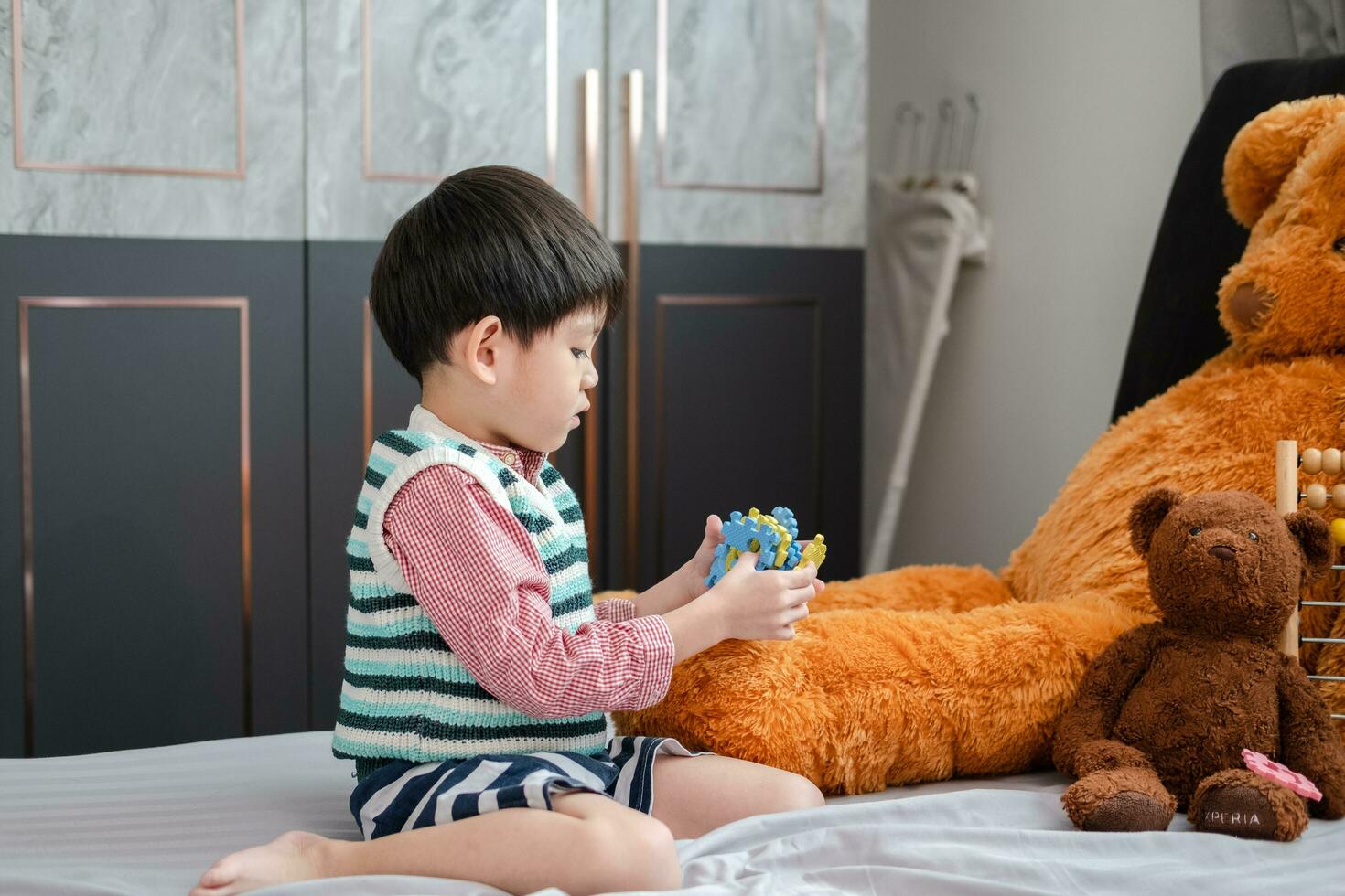 asiatisk pojke spelar med kontursåg pussel på de säng glatt foto