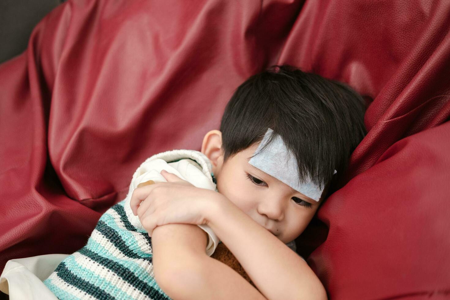 asiatisk pojke hon var sjuk och hade en feber minska lappa på henne panna. hon var liggande på de säng. foto