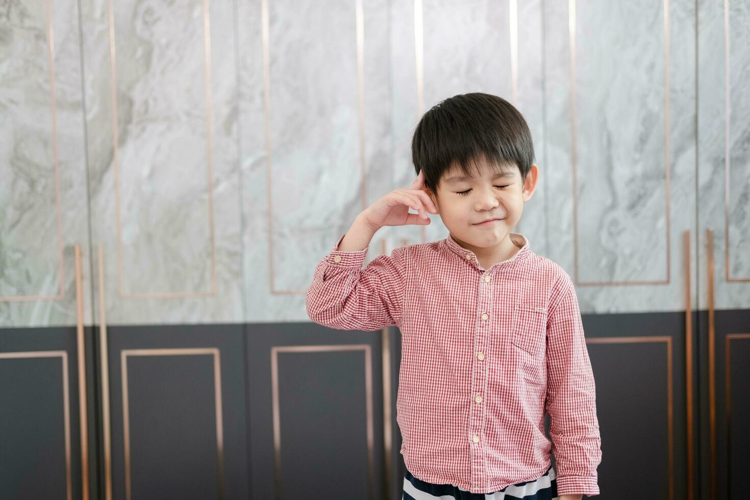 asiatisk pojke står med hans hand pekande på hans huvud. låtsas till vara tänkande handla om något foto