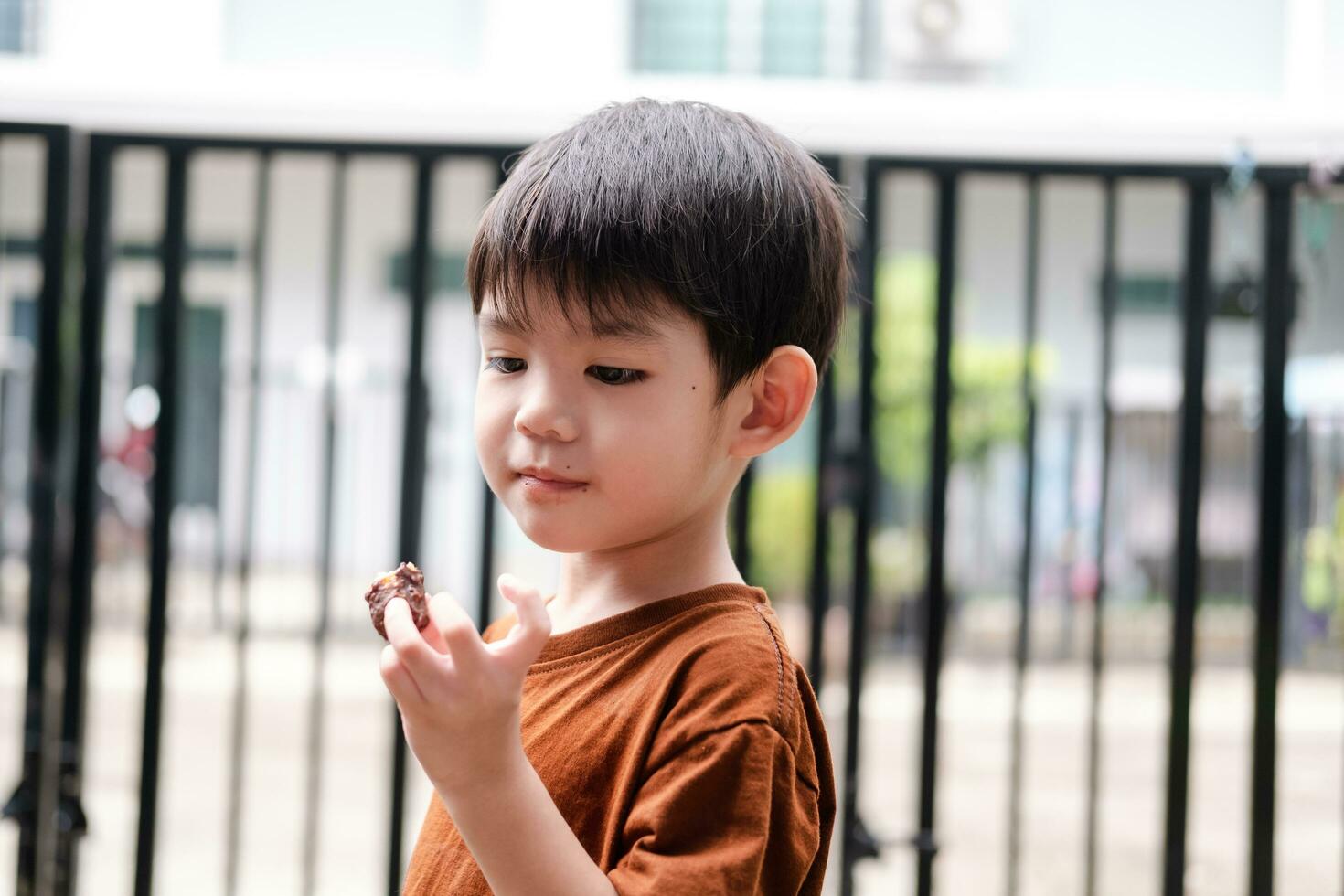 Lycklig ansikte av asiatisk pojke äter choklad godis foto