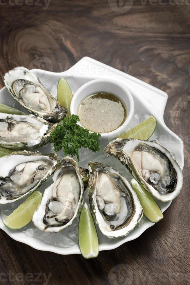 sex färska ostron med limeskivor och citrusvinaigrette sås foto