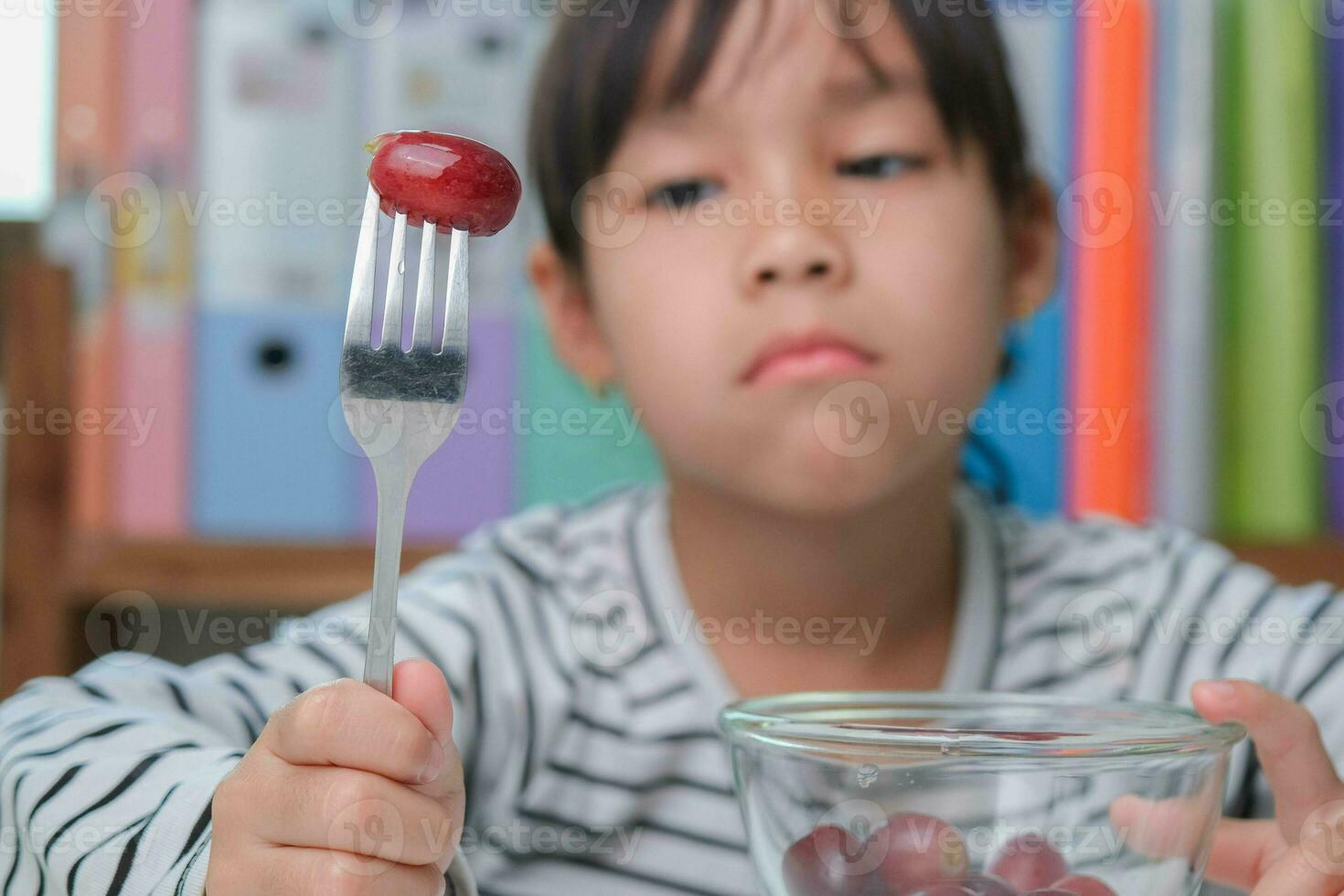 barn inte tycka om till äta frukter. söt ung asiatisk flicka vägrar till äta friska frukter. näring och friska äter vanor för barn. foto