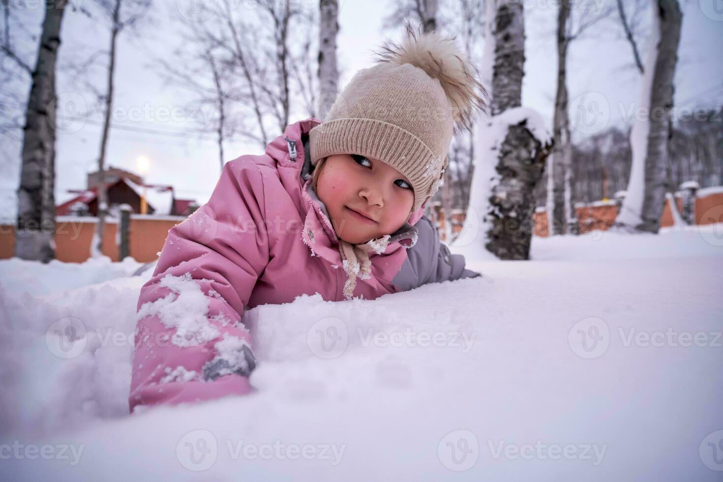 en flicka spelar i djup snö i de gård. foto