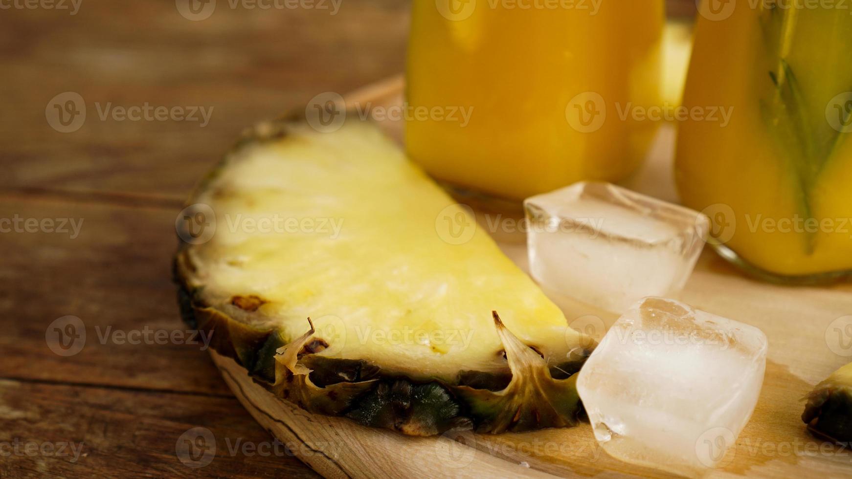 färska ananasskivor och och isbitar på en träbakgrund foto