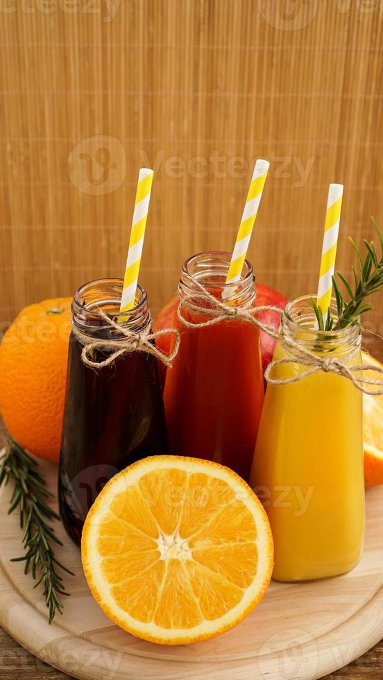 hemgjord limonad i små flaskor. mångfärgade juicer och frukter foto