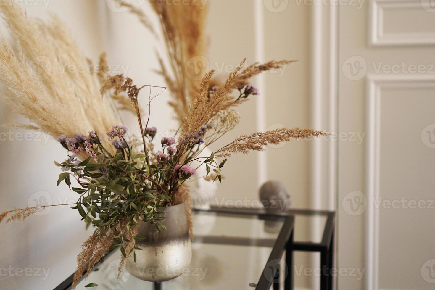 söta små torkade blommor i liten glasvas i vardagsrummet foto