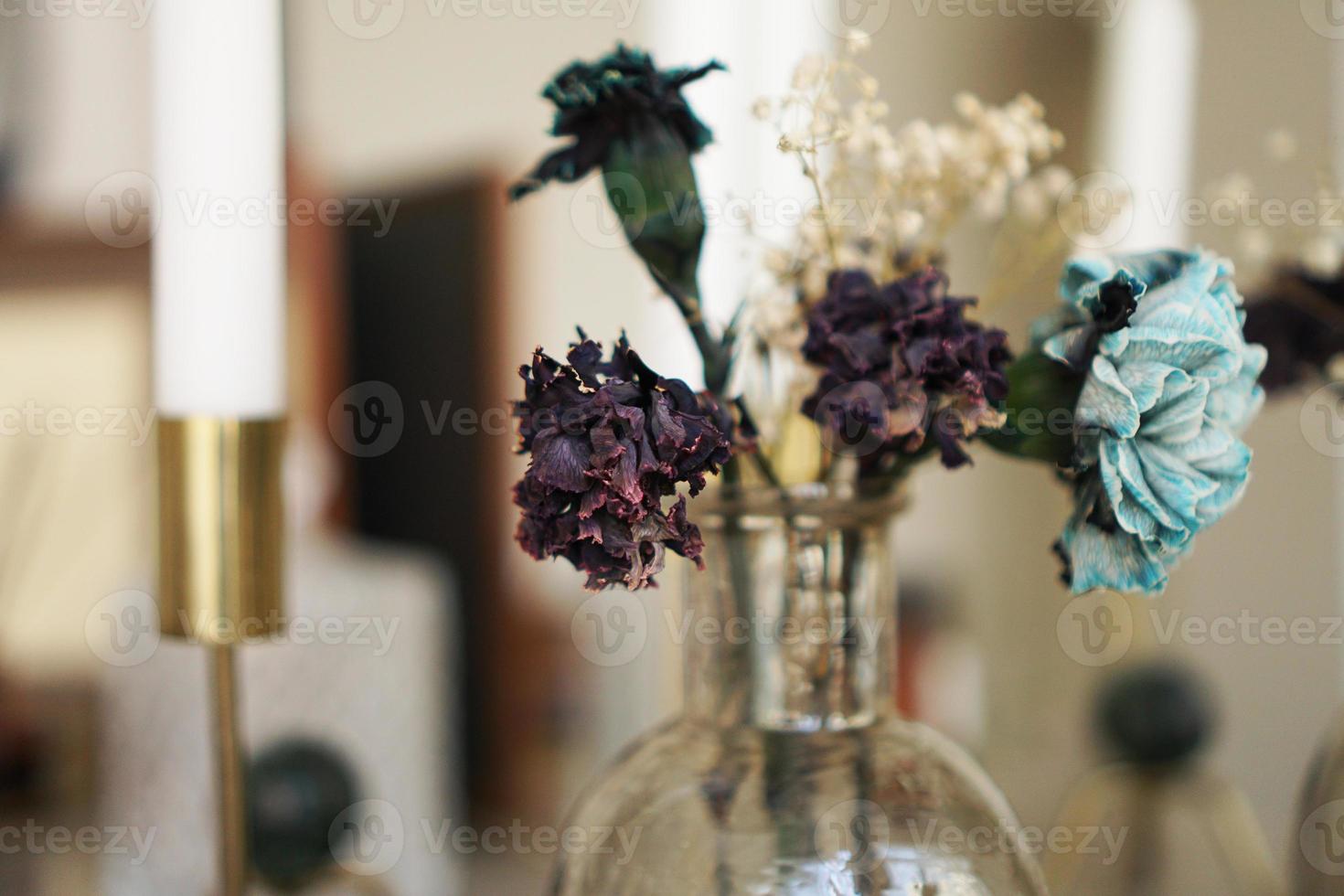 heminredning. glasburk med torkade blommor, vas och ljus foto