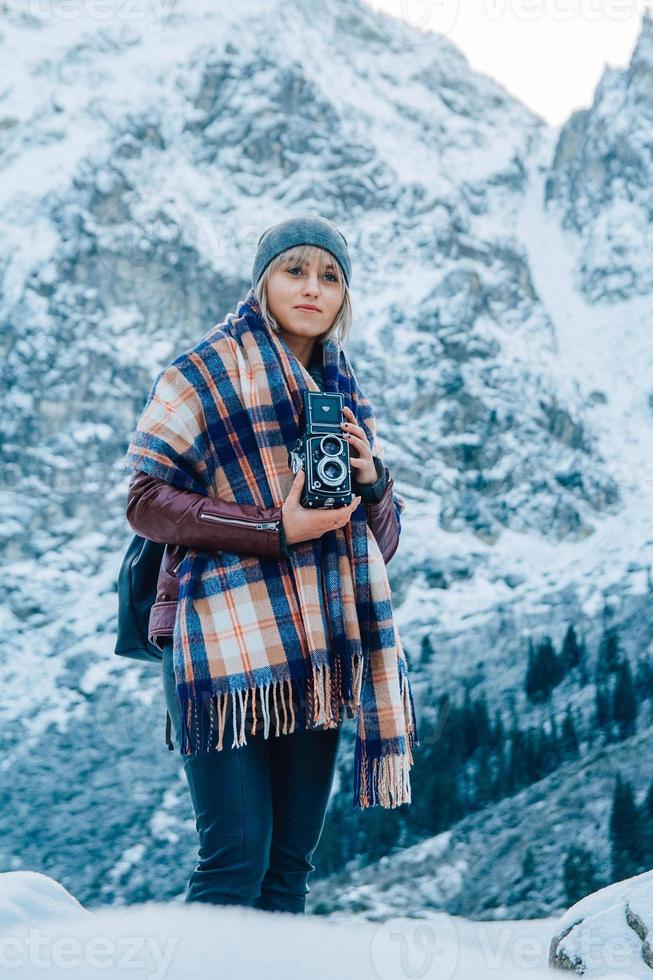 flicka med gammal vintagekamera på en bakgrund av snöbergen foto