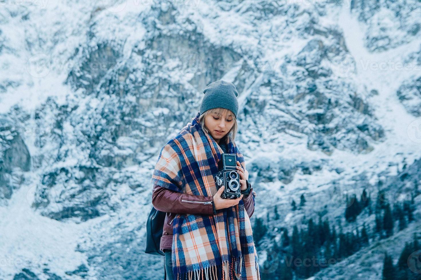 flicka med gammal vintagekamera på en bakgrund av snöbergen foto