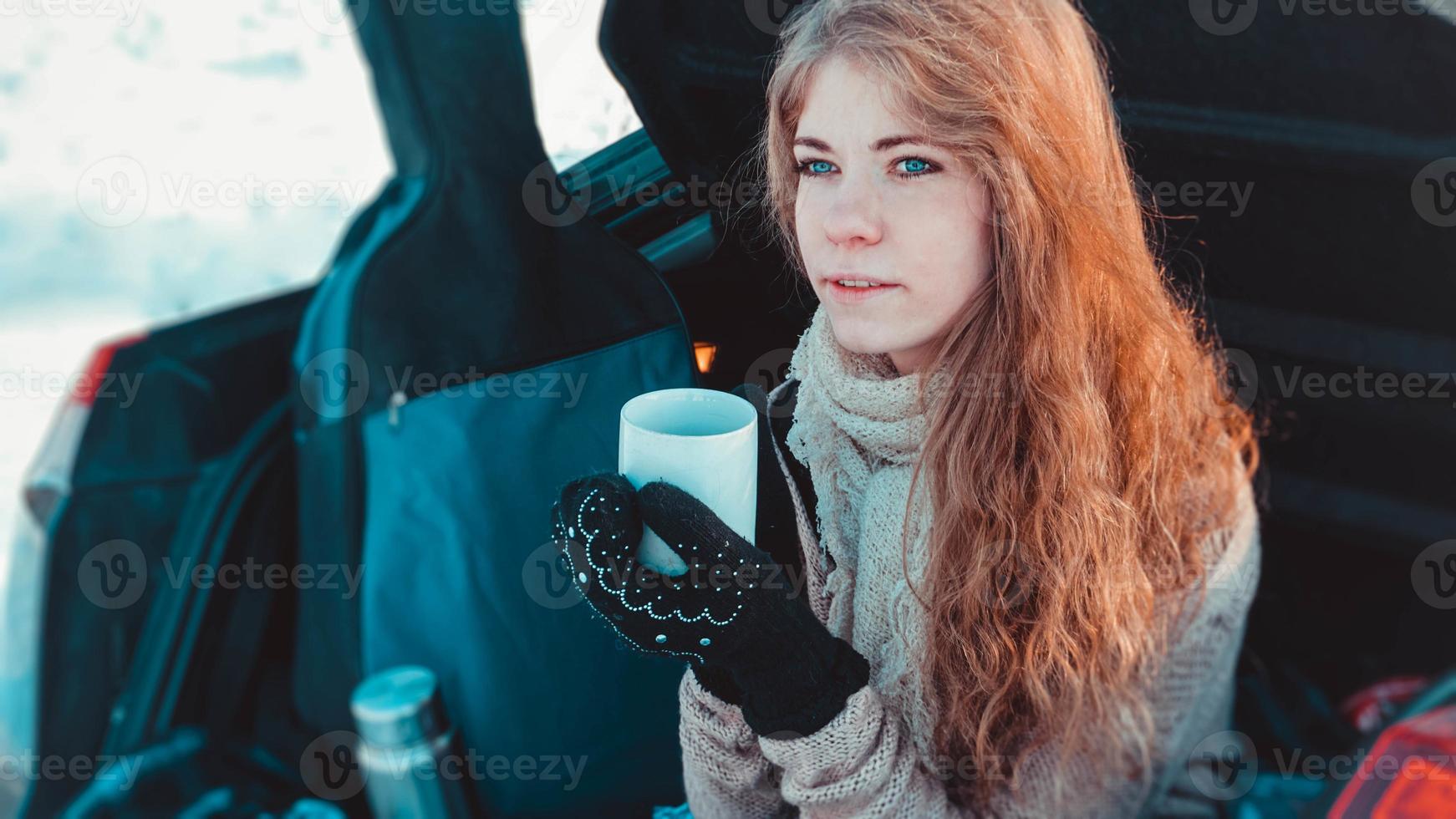 glad tjej sitter på lastbil med bil i vinterskogen foto