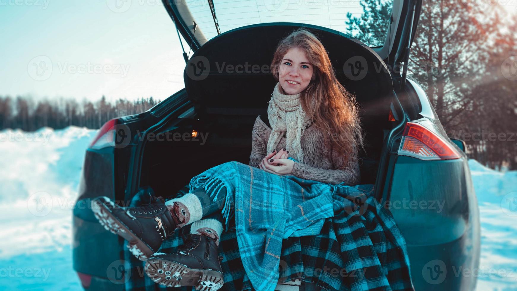 glad tjej sitter på lastbil med bil i vinterskogen foto