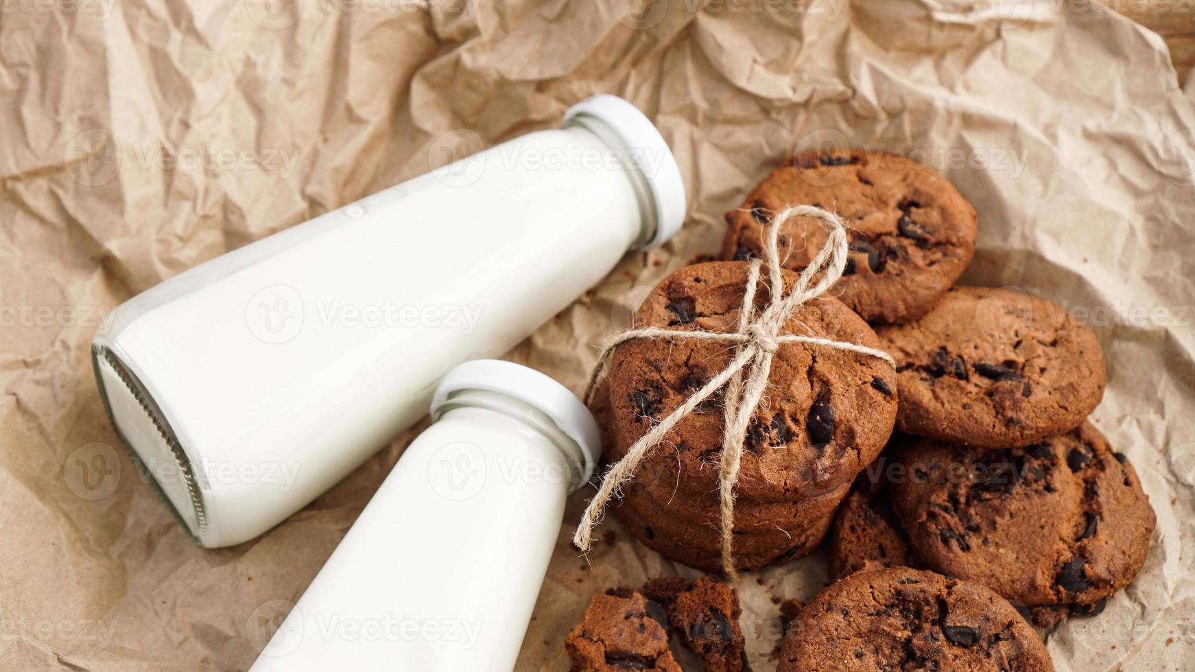 kakor med chokladdroppar på papper och flaskor mjölk foto