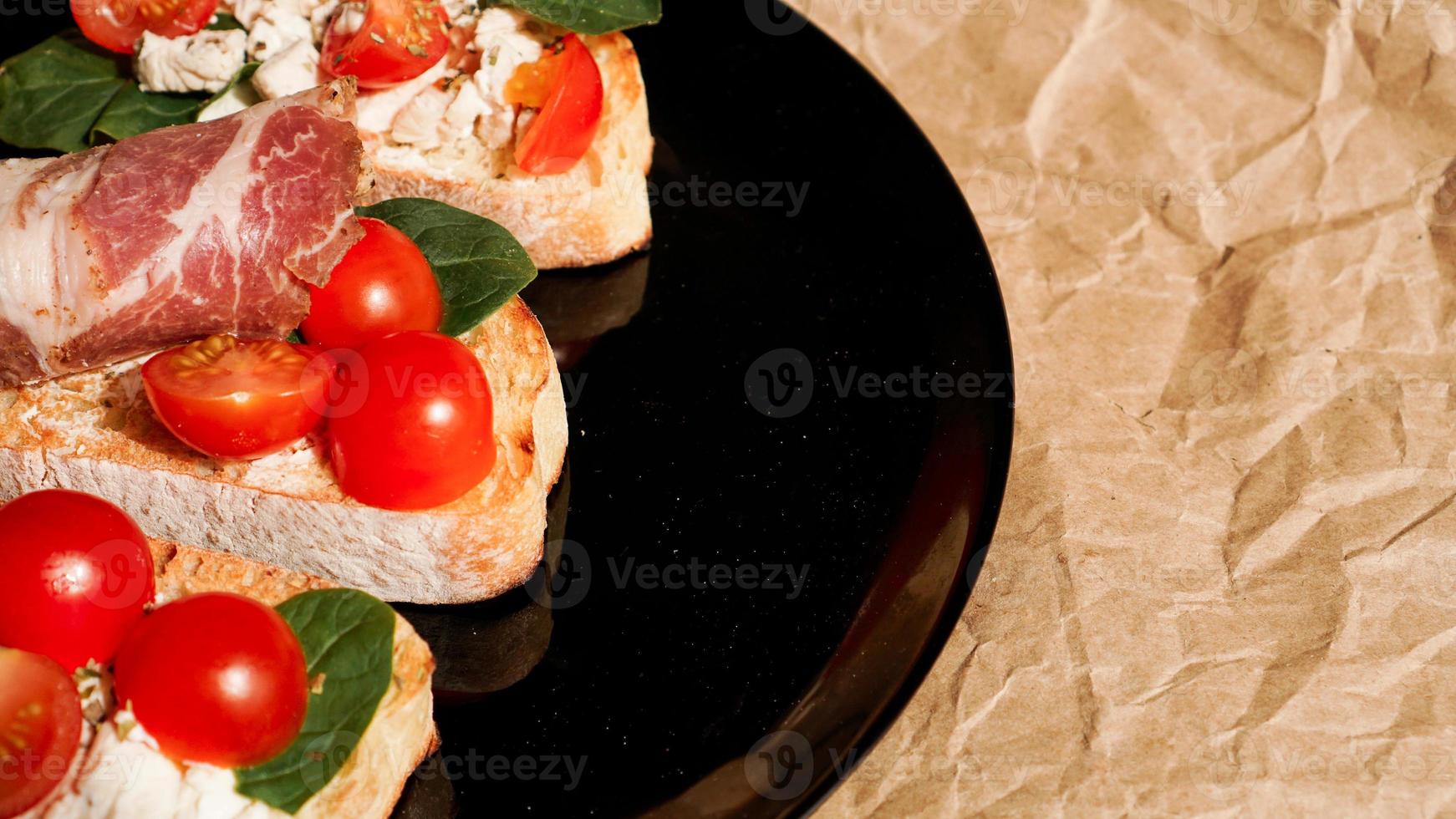 tre bruschetta på en svart tallrik på papper foto