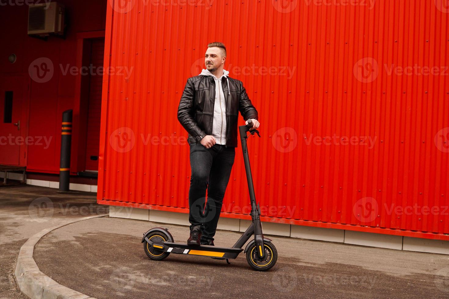 ung attraktiv man på elektrisk scooter över röd bakgrund foto