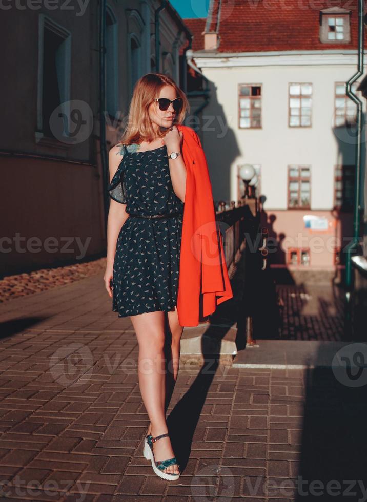 ganska ung kvinna i röd jacka på stadsgatan urban bakgrund foto