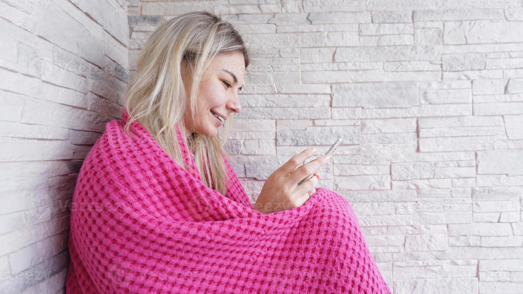 vacker flicka sitter på fönsterbrädan med smartphone i händerna. foto