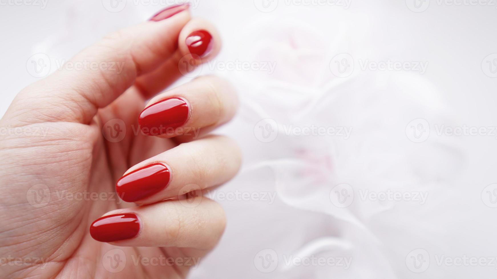 vacker kvinnlig hand med röda naglar mot bröllopsbukett foto