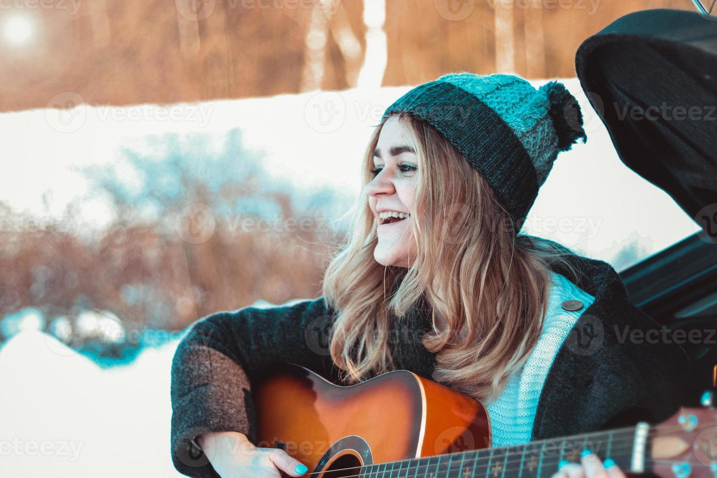 flicka som spelar gitarr som sitter på bilens bagagerum foto