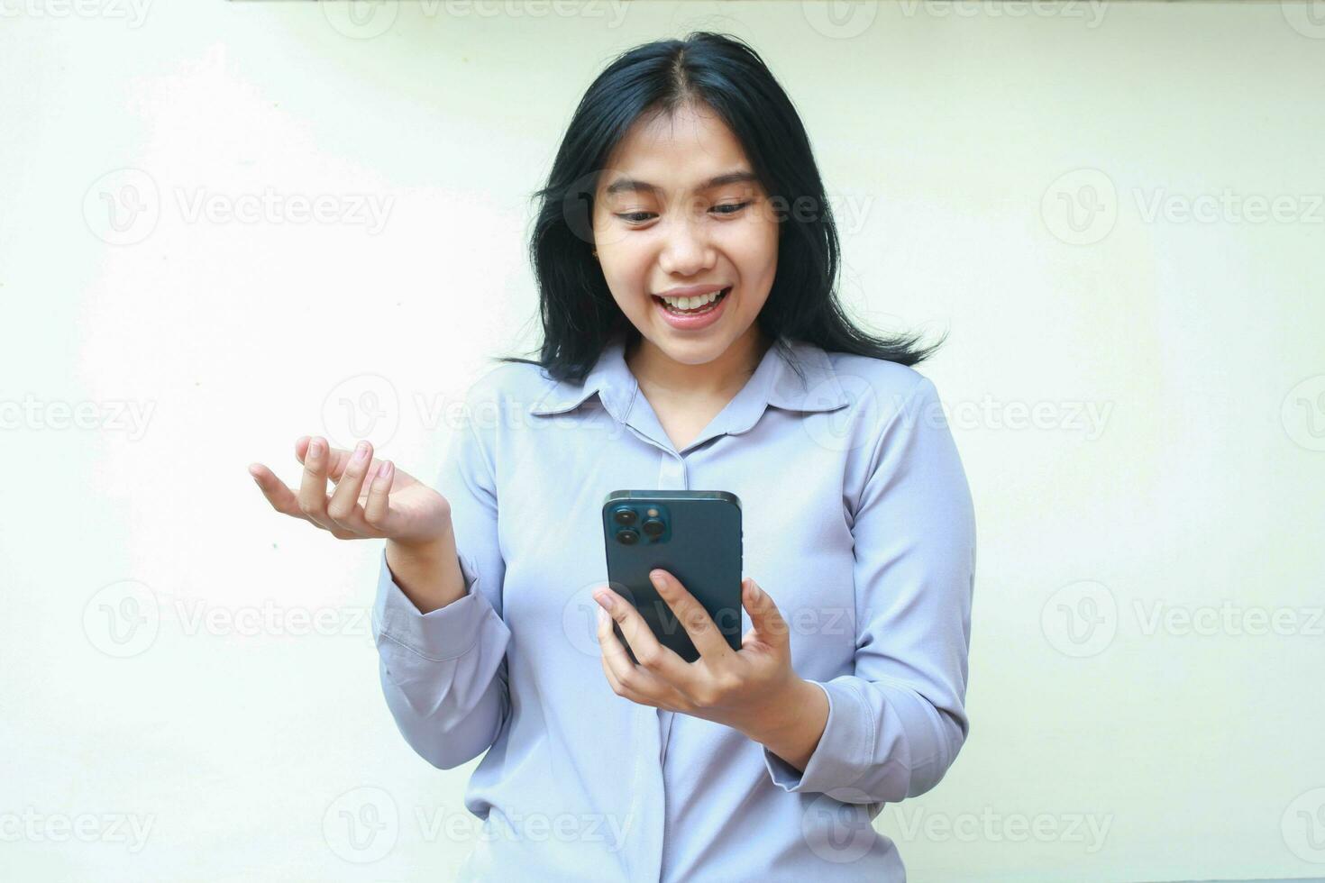 upphetsad ung asiatisk företag kvinna använder sig av smartphone till video ring upp uppkopplad möte bär formell skjorta med höjning öppen handflatan, förklara gest, stående över isolerat vit bakgrund foto