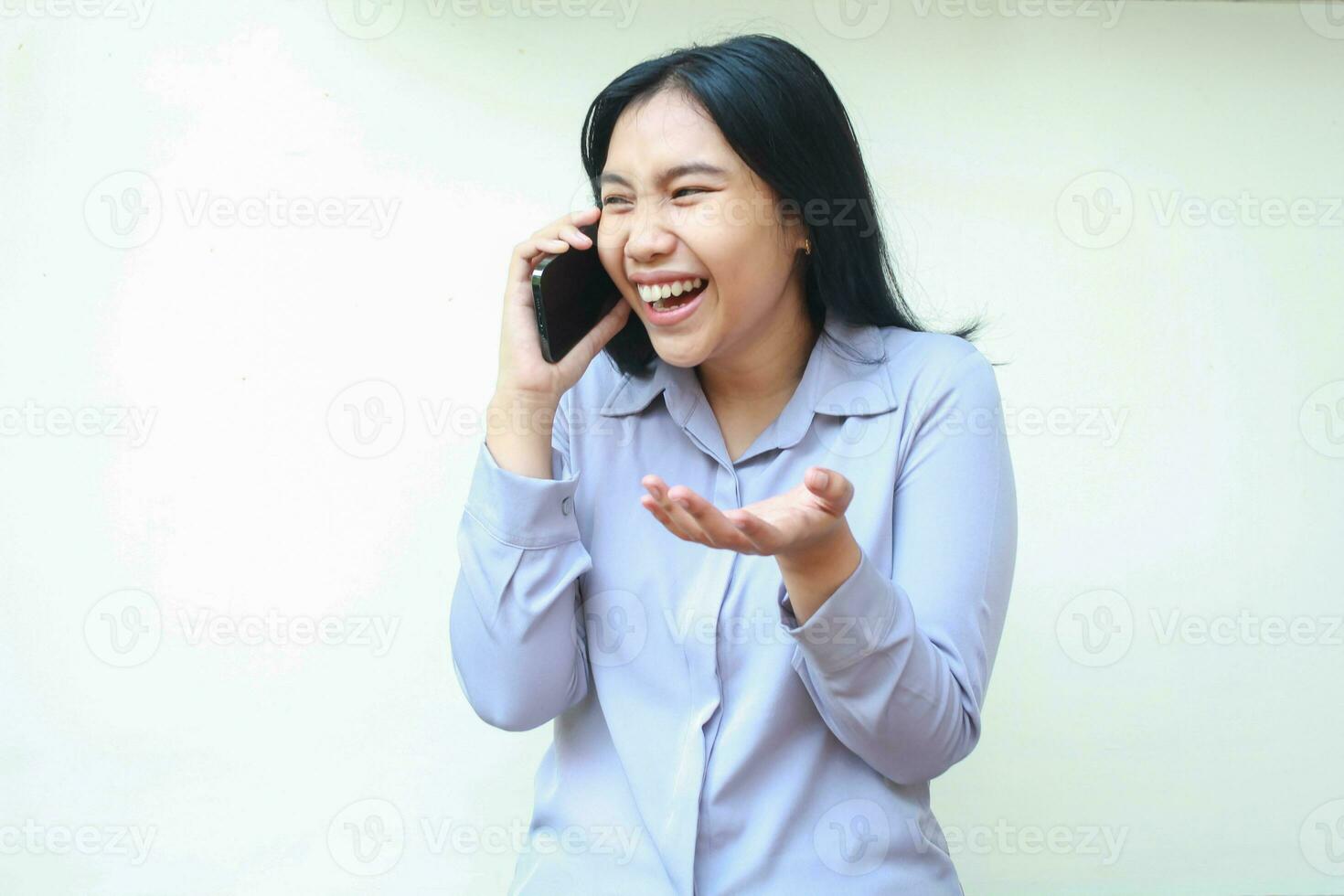 studio skott av skrattande asiatisk ung företag kvinna tala på mobiltelefon leende brett ser bort ha på sig lila formell kontor skjorta stående över isolerat vit bakgrund foto