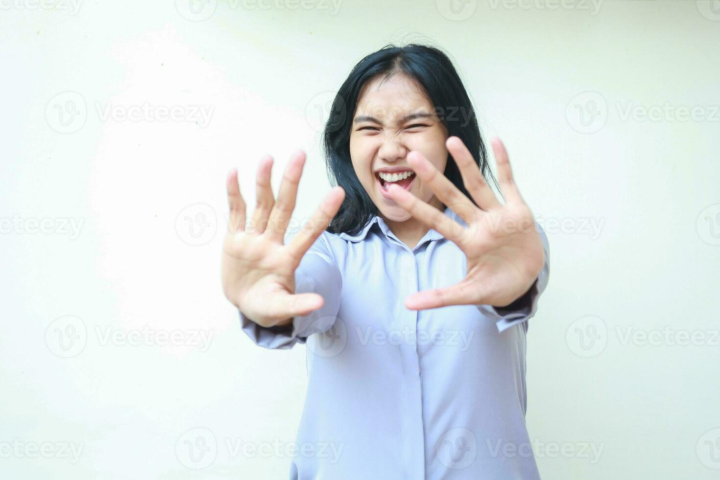 studio skott av bedövad asiatisk ung skön företag kvinna nå händer mot kamera leende förvånad bär formell kontor skjorta stående över isolerat vit bakgrund foto