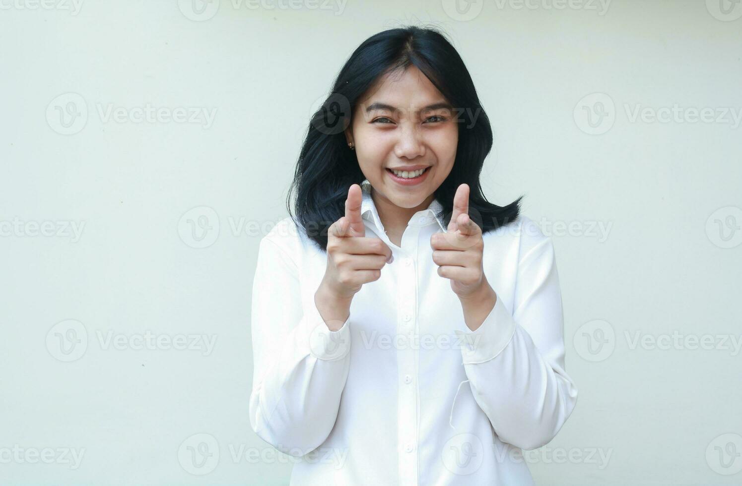 lekfull asiatisk ung företag kvinna upphetsad pekande pekfinger och tummen upp till kamera bär vit formell kostym skjorta, dess du gest, isolerat i vit bakgrund, reklam begrepp foto