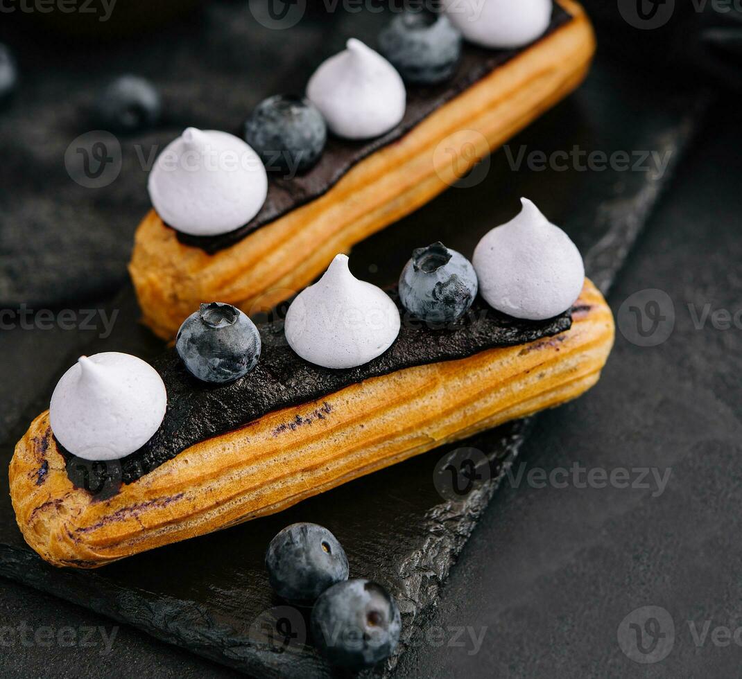 skön och gott eclairs på en skiffer styrelse med kronblad foto