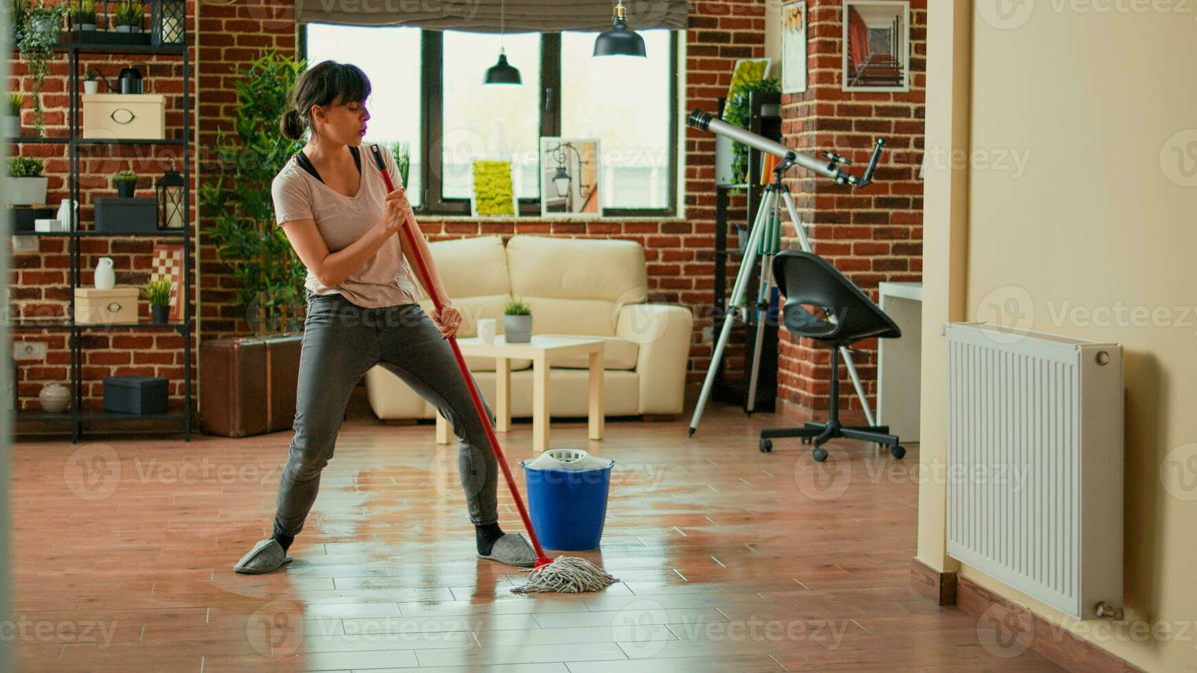 Lycklig rolig person moppning golv med Allt ändamål rengöringsmedel och dans, vår rengöring. ung glad hemmafru använder sig av mopp till sopa smuts och rena röra, lyssnande till musik på Hem. foto