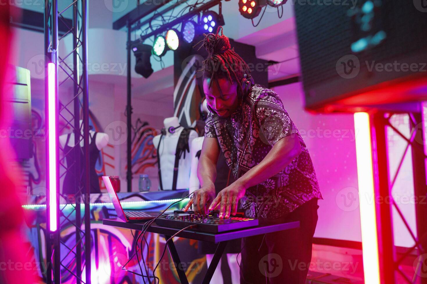 afrikansk amerikan musiker utför leva på skede med spotlights på klubb använder sig av mixer trösta. man dj brådskande knappar på kontrollant medan blandning ljud på nattklubb disko fest foto